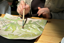 <p>Blatt Papier mit gemalten Pflanzen und Hand mit Pinsel</p>